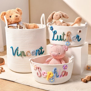 Puede incluir: Tres cestas de almacenamiento de cuerda de algod&oacute;n tejida blanca con asas. Las cestas presentan nombres bordados de colores: Vincent, Luther y Sophia. Cada cesta est&aacute; decorada con peque&ntilde;as flores de tela y contiene un peluche: un oso, un conejo y un cerdo.