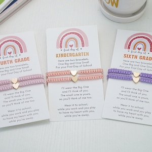 May include: Three cards with rainbow designs and the words "First Day of" followed by "Fourth Grade", "Kindergarten", and "Sixth Grade". Each card has two friendship bracelets with gold heart charms. The cards have a poem about wearing the bracelets to school.