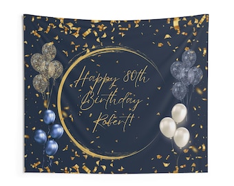 May include: Navy blue tapestry with gold confetti and balloons. The text "Happy 80th Birthday Robert!" is written in gold script inside a gold circle. Clusters of blue, clear, and white balloons are on the tapestry.