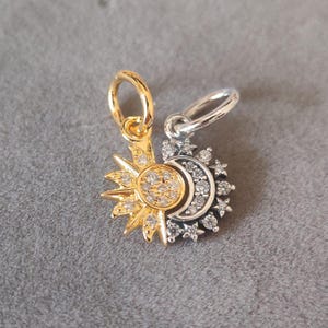 May include: A gold and silver charm featuring a sun and moon design with clear crystals. The charm has a loop for attaching to a bracelet or necklace.