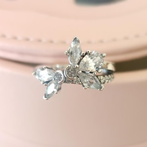 Puede incluir: Un anillo de plata con un delicado diseño de mariposa con piedras de circonita cúbica transparentes.