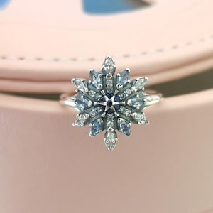 May include: A silver ring with a snowflake design featuring blue and white crystals.