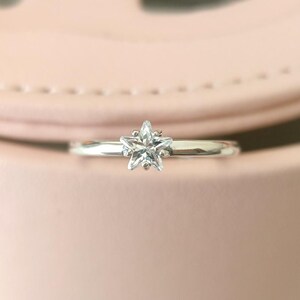 Puede incluir: Un anillo de plata con una piedra preciosa transparente en forma de estrella.
