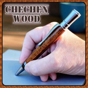 May include: A wooden pen with a silver clip and tip is held in a hand. The pen has a dark brown, wood-grain barrel and the text "CHECHEN WOOD" is displayed at the top of the image.