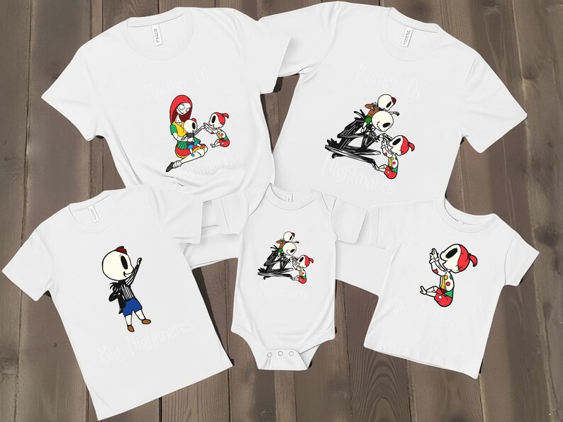 May include: White t-shirts and a onesie featuring cartoon characters in various poses. The designs include a skeleton character and other figures in colorful outfits. The shirts are likely for a family or group.