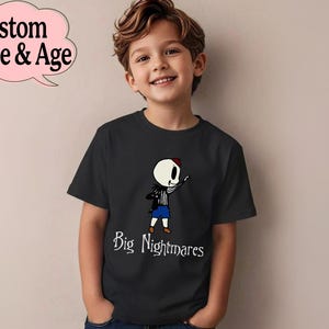 May include: Black t-shirt featuring a cartoon skeleton character with a red hat, black jacket, and blue shorts. The text "Big Nightmares" is below the character. A pink speech bubble with "Custom Name & Age" is in the upper left.