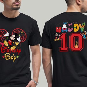 May include: Black t-shirt featuring Mickey Mouse with the text "Birthday Boy" in red and yellow. The back of the shirt displays the number "10" in red, along with various Disney characters, perfect for a birthday celebration.