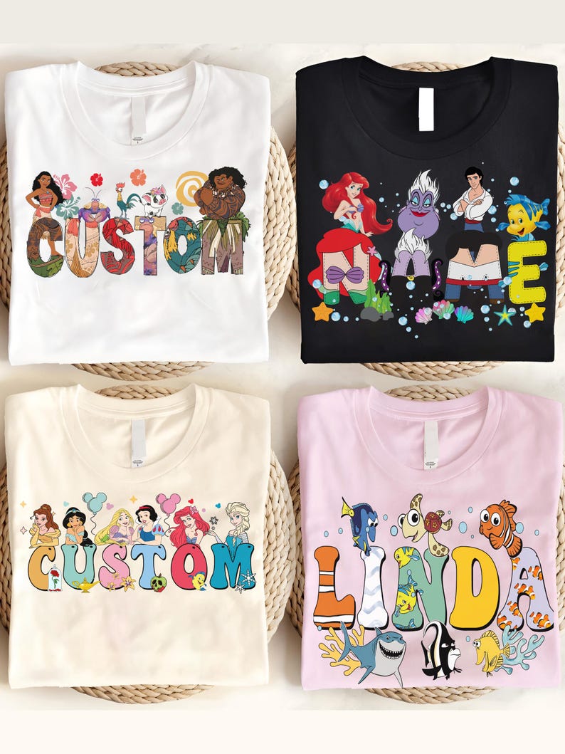K&ouml;nnte beinhalten: Vier T-Shirts mit farbenfrohen Grafikdesigns. Ein wei&szlig;es T-Shirt mit dem Wort "CUSTOM" und Disney-Figuren. Ein schwarzes T-Shirt mit Disney-Figuren und dem Wort "ME". Ein cremefarbenes T-Shirt mit Disney-Prinzessinnen und dem Wort "CUSTOM". Ein rosa T-Shirt mit Meeresbewohnern und dem Namen "LINDA".