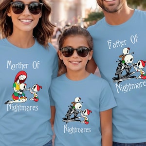 May include: Three light blue t-shirts with matching graphics. The shirts feature the text "Mother Of Nightmares" and "Father Of Nightmares" with a cartoon illustration of characters. The shirts are for a family.