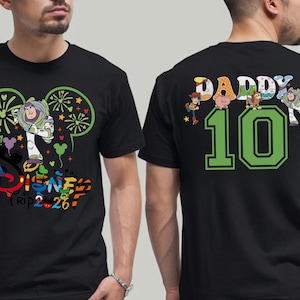 May include: Black t-shirt with a Disney design. The front shows Buzz Lightyear and the text "Disney Trip 2.26". The back has "DADDY 10" with Toy Story characters. A colourful tee, perfect for a Disney enthusiast.