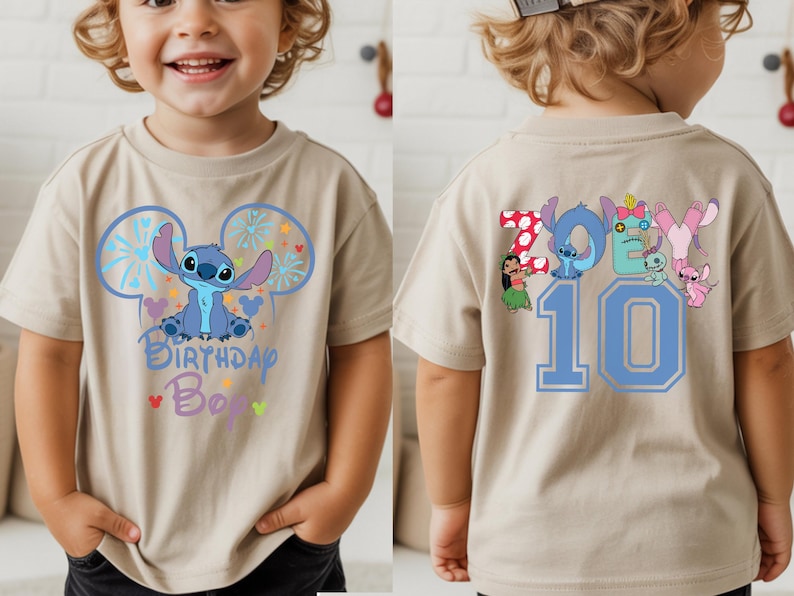 May include: Tan short-sleeved t-shirt featuring a blue cartoon character design with the text "Birthday Boy" on the front. The back of the shirt displays the name "Zoey" and the number "10" in blue.