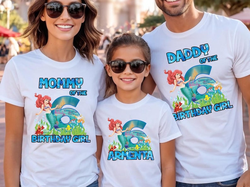 May include: White t-shirts with a mermaid theme. Each shirt has a different text: "Mommy of the Birthday Girl", "Daddy of the Birthday Girl", and a personalized name. The number "6" is featured prominently.
