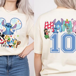 May include: A cream-coloured t-shirt with a blue Stitch character design, fireworks, and the text "Disney Trip". The back of the shirt shows the word "MAMA" with Disney characters and the number "10" in blue.