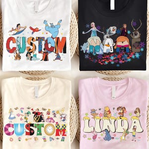 K&ouml;nnte beinhalten: Vier T-Shirts mit Zeichentrickfiguren-Designs. Ein wei&szlig;es T-Shirt mit "CUSTOM" in bunten Buchstaben und Aladdin-Figuren. Ein schwarzes T-Shirt mit "NAME" und Frozen-Figuren. Ein cremefarbenes T-Shirt mit "CUSTOM" und Alice im Wunderland-Figuren. Ein rosa T-Shirt mit "LINDA" und Winnie-the-Pooh-Figuren.