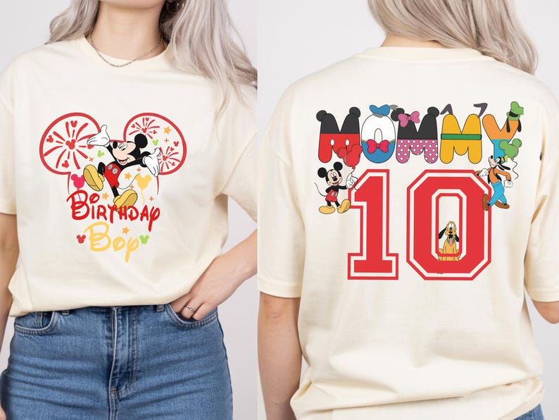 May include: Cream-colored t-shirt featuring Mickey Mouse with fireworks and the text "Birthday Bop" in red and yellow. The back of the shirt displays the word "Mommy" and the number "10" with Disney characters.