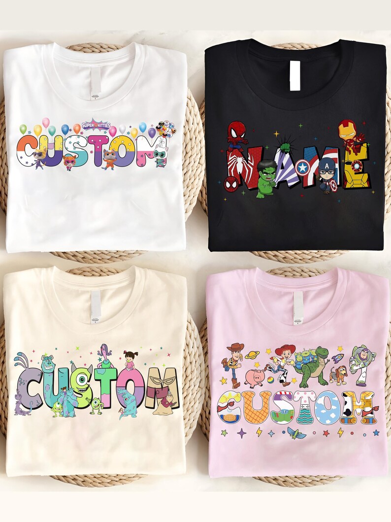 K&ouml;nnte beinhalten: Vier T-Shirts mit individuellen Designs. Ein wei&szlig;es T-Shirt zeigt das Wort "CUSTOM" mit Cartoon-Figuren und Luftballons. Ein schwarzes T-Shirt hat "NAME" mit Marvel-Charakteren. Ein beiges T-Shirt sagt "CUSTOM" mit Monster-Charakteren. Ein rosa T-Shirt sagt "CUSTOM" mit Toy Story-Charakteren.