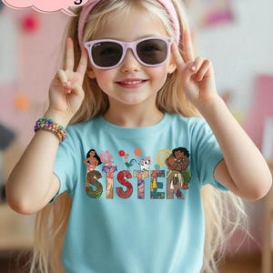 May include: A light blue t-shirt with the word "SISTER" in colorful letters, featuring cartoon characters. The shirt is worn by a young girl wearing pink sunglasses and a matching headband. The image includes the text "Custom Name & Age".