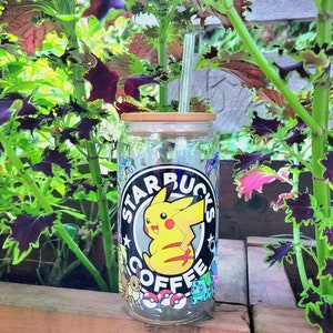 May include: A clear glass tumbler with a bamboo lid and a straw. The tumbler has a graphic of Pikachu from Pokemon and the text "Starbucks Coffee".