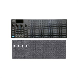 May include: A black electronic music production controller featuring a grid of square buttons, four rotary knobs, a small display screen, and various function buttons labelled with text, accompanied by a matching dark grey felt cover.