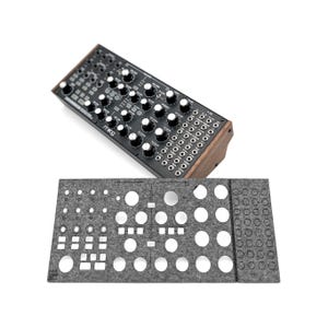 Könnte beinhalten: Ein schwarzer und silberner Synthesizer mit einer Holzseitenteil. Der Synthesizer verfügt über eine Vielzahl von Knöpfen, Tasten und Buchsen. Ein graues Filzpad mit Ausschnitten für den Synthesizer ist ebenfalls abgebildet.