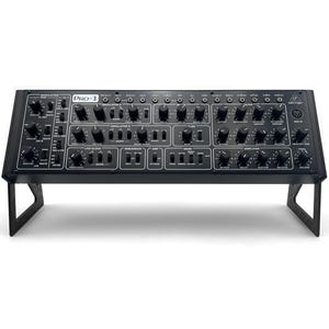 以下が含まれることがあります： 「PRO-1」とラベルされた、多数のノブ、スライダー、ボタンを備えた黒いシンセサイザー。電子楽器は黒いスタンドに取り付けられています。シンセサイザーには、変調、発振器、フィルター用のさまざまなコントロールがあります。