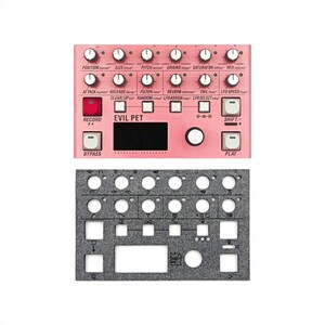 May include: A pink electronic audio processor with numerous knobs, buttons, and a display screen. The text "EVIL PET" is printed on the device. Below it is a gray felt panel with cutouts for the controls.