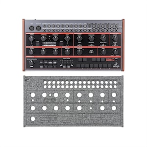 May include: A black and brown synthesizer with numerous knobs, buttons, and ports, labeled "GRIND" and "Behringer." Below it is a gray felt panel with cutouts for the controls. The synthesizer has a wooden frame.