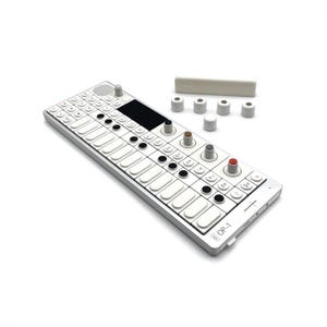 Könnte beinhalten: Ein silber-weißes OP-1-Synthesizer mit weißen Tasten, schwarzen Knöpfen und verschiedenen Knöpfen. Das Gerät hat einen schwarzen Bildschirm und der Text "OP-1" ist sichtbar. Weiße Ersatzteile sind ebenfalls enthalten.
