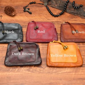 May include: Five leather coin purses in different colors: black, red, brown, dark brown, and yellow brown. Each purse has a zipper closure and a small tassel.