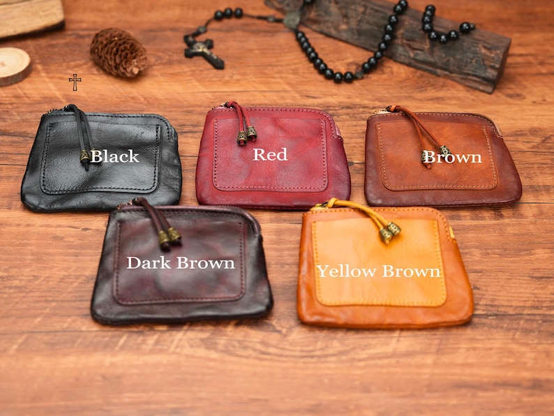 May include: Five leather coin purses in different colors: black, red, brown, dark brown, and yellow brown. Each purse has a zipper closure and a small tassel.