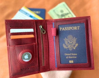 May include: A red leather passport holder with a zippered pocket, two card slots, and a RFID blocking patch. The holder has a built-in passport sleeve with a clear window to display the passport photo. The passport sleeve has the word "PASSPORT" printed in gold letters.