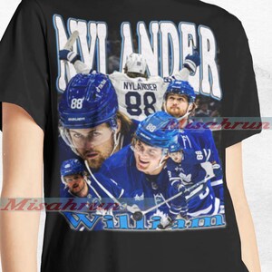 May include: Black t-shirt with a graphic of hockey player William Nylander wearing a Toronto Maple Leafs jersey. The graphic includes the text "Nylander" and "William".