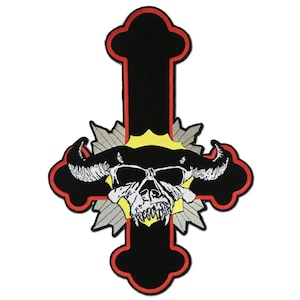 May include: Black cross-shaped patch with a red border, featuring a white skull with horns and a yellow and gray background. The patch is designed with a gothic or heavy metal theme, suitable for jackets or bags.
