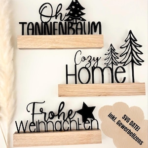 May include: Three wooden shelves with black cut-out words and Christmas tree designs. The words include "Oh Tannenbaum", "Cozy Home", and "Frohe Weihnachten". A star is included in the "Frohe Weihnachten" design. The image also includes the text "SVG DATEI inkl. Gewerbelizenz".