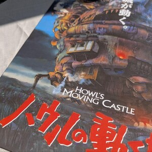 May include: A poster featuring the animated film "Howl's Moving Castle." The artwork depicts the castle with a complex, mechanical design, set against a landscape with a blue sky. The title is displayed in English and Japanese.