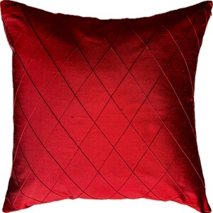 May include: Red decorative pillow with a diamond pattern. The pillow is made of a soft, silky fabric.