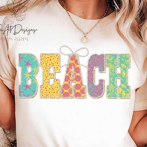 Puede incluir: Una camiseta color crema con la palabra "BEACH" en letras coloridas y estampadas. Las letras están delineadas con un borde perlado. La "B" es turquesa con estrellas de mar rosas, la "E" es amarilla con lunares, la "A" es rosa con conchas, la "C" es morada con un diseño floral y la "H" es verde azulado con hojas.