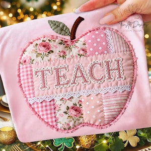 Könnte beinhalten: Rosa apfelförmige Lehrertasche mit dem Wort "TEACH" in Rosa gestickt. Das Apfeldesign weist Stoffflicken mit Blumen-, Tupfen- und Streifenmustern sowie ein grünes Blatt und einen braunen Stiel auf.