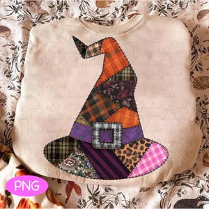 Puede incluir: Una sudadera beige con un diseño de sombrero de bruja de patchwork. El sombrero está compuesto por varios patrones de tela, incluyendo cuadros, flores y estampado de leopardo, con acentos naranjas, morados y rosas. El sombrero tiene una hebilla plateada y está cosido a la camisa.