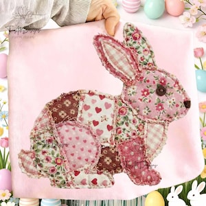 May include: A patchwork bunny rabbit with a button eye and floral and heart patterns. The bunny is made of various fabrics in shades of pink, red, and brown. The background is a soft pink.