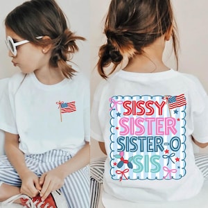 May include: White t-shirt with an American flag graphic on the front and the words "SISSY SISTER SISTER-O SIS" on the back. The design includes stars, bows, and a balloon dog.