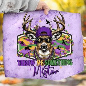 May include: A purple and green graphic featuring a deer wearing a purple cap, sunglasses, and Mardi Gras beads. The deer is set against a camouflage background with the text "THROW ME SOMETHING Mister".
