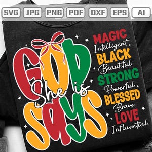 May include: Black sweatshirt with the text "GOD says She is" in red, yellow, and green. The words "MAGIC, Intelligent, BLACK, Beautiful, STRONG, Powerful, BLESSED, Brave, LOVE, Influential" are also printed on the shirt.