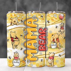 May include: A yellow and gold stainless steel tumbler with a Winnie the Pooh theme. The tumbler features a honeycomb pattern, daisies, and Winnie the Pooh characters. The text "Mama Bear" is printed on the tumbler.