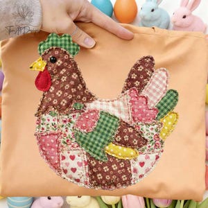 May include: A peach-coloured tote bag with a patchwork chicken design. The chicken is made of various patterned fabrics in shades of brown, pink, green, and white. The chicken has a green comb, yellow beak, and red wattle. The bag is decorated with Easter-themed items.