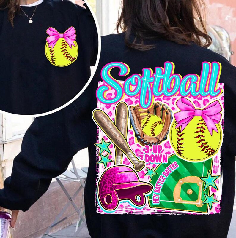 May include: Black sweatshirt with a softball theme. The design includes a yellow softball with a pink bow, a pink helmet, bats, a glove, and the word "Softball" in turquoise. The background has a pink leopard print.
