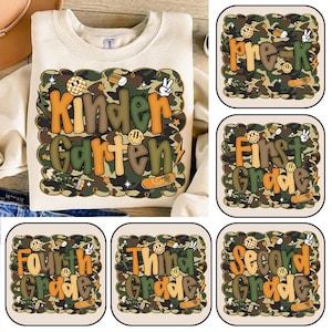 Könnte beinhalten: Ein beiges Sweatshirt mit einem farbenfrohen Aufdruck mit der Aufschrift "Kindergarten" in orangefarbenen und grünen Buchstaben. Die Grafik hat einen Camouflage-Hintergrund mit Smiley-Gesichtern, Bleistiften und Skateboards. Zusätzliche Grafiken zeigen "Pre-K", "First Grade", "Second Grade", "Third Grade" und "Fourth Grade".