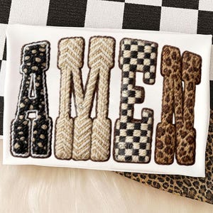 Könnte beinhalten: Ein weißes, rechteckiges Objekt mit dem Wort "AMEN" in einer kräftigen, strukturierten Schriftart. Die Buchstaben haben verschiedene Muster: schwarz-weiße Punkte, gewebtes Beige, schwarz-weißes Schachbrettmuster und Leopardenmuster.