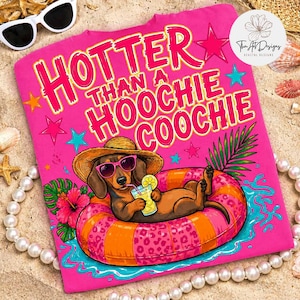 May include: A hot pink t-shirt with the text "HOTTER THAN A HOOCHIE COOCHIE" in large pink letters. The shirt features a cartoon dachshund wearing sunglasses and a straw hat, relaxing on an inflatable ring. The shirt is decorated with stars and tropical flowers.