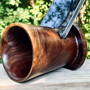 May include: A wooden phone amplifier made from dark walnut wood. The amplifier has a round opening on one side and a slot for a phone on the other side. The phone is not included.